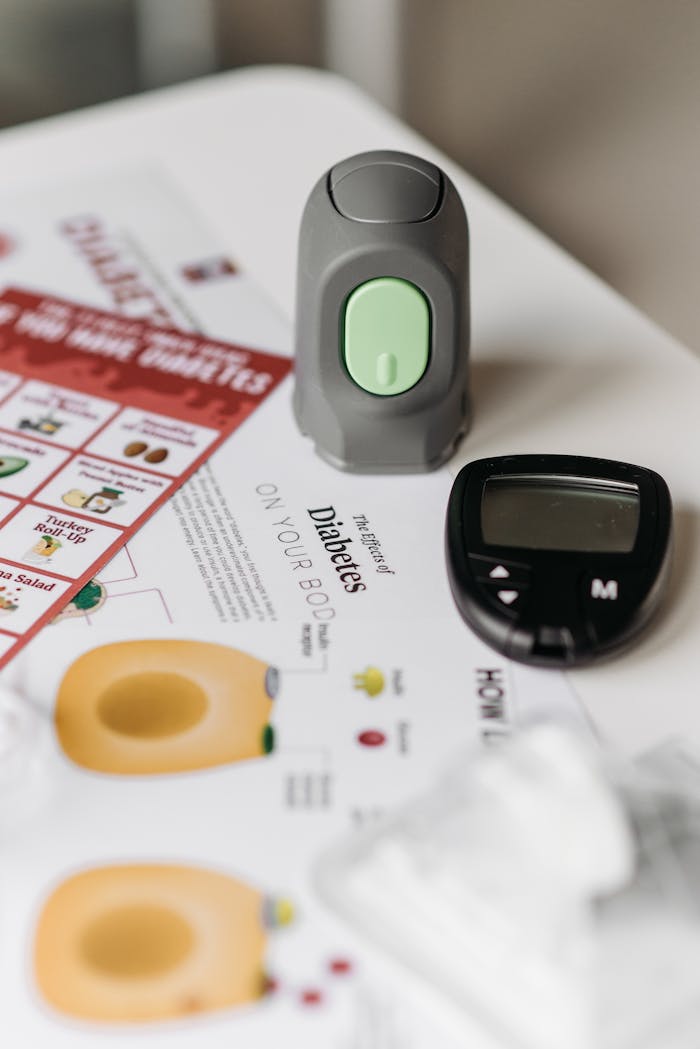 Glucometer and diabetes documents on a table for health monitoring.